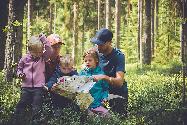 En familj är ute i skogen och läser tillsammans på en karta.